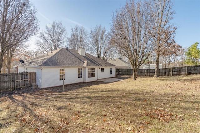 rear view of property featuring a chimney, a patio area, and roof with shingles