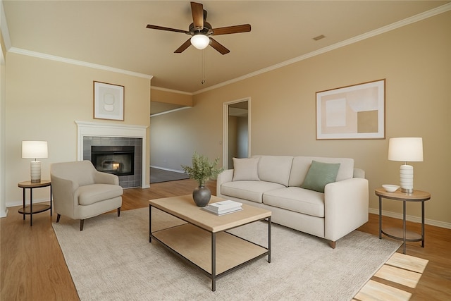 living area with a ceiling fan, light wood-style floors, baseboards, and crown molding