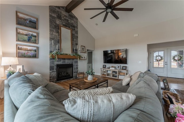 living room with a stone fireplace, high vaulted ceiling, beamed ceiling, wood-type flooring, and ceiling fan