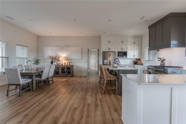 kitchen featuring sink, light wood-type flooring, white cabinets, stainless steel appliances, and backsplash