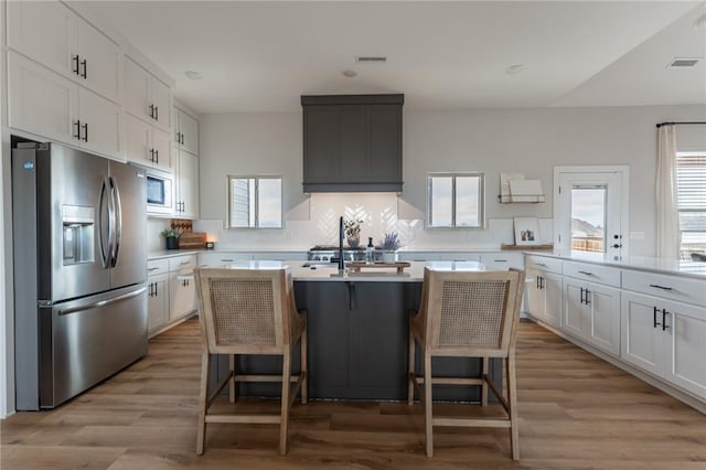 kitchen featuring white cabinetry, a center island with sink, a breakfast bar area, and appliances with stainless steel finishes