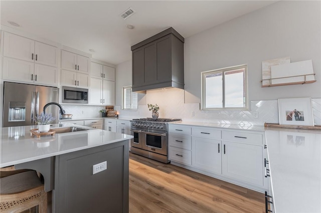 kitchen with tasteful backsplash, white cabinetry, sink, a breakfast bar area, and stainless steel appliances