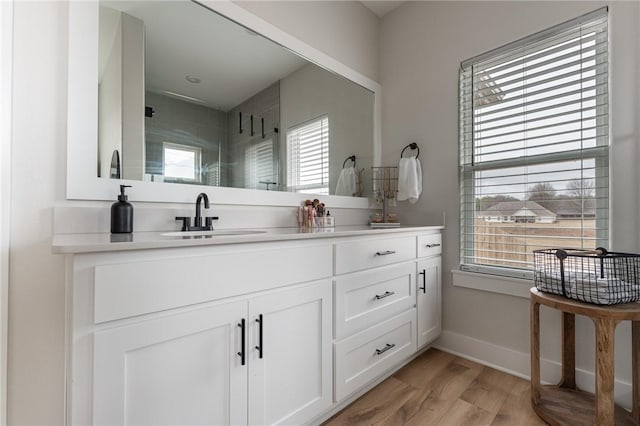 bathroom featuring vanity, wood-type flooring, a healthy amount of sunlight, and walk in shower