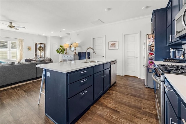 kitchen featuring an island with sink, sink, stainless steel appliances, crown molding, and blue cabinetry