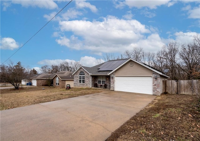 ranch-style house with a garage, a front yard, and solar panels