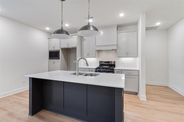 kitchen featuring pendant lighting, an island with sink, stainless steel range with gas cooktop, and sink