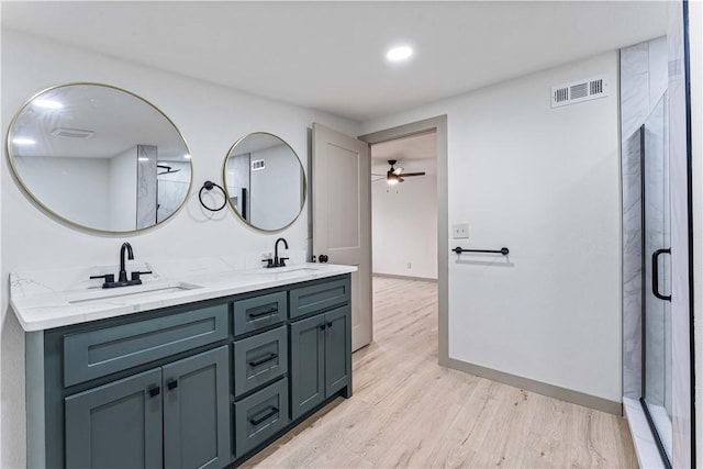 bathroom with vanity, hardwood / wood-style flooring, a shower with shower door, and ceiling fan