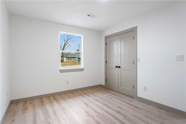 unfurnished bedroom with light hardwood / wood-style flooring and a closet