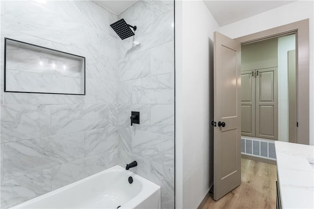 bathroom with hardwood / wood-style flooring and tiled shower / bath