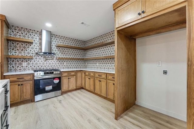 kitchen featuring tasteful backsplash, gas stove, light hardwood / wood-style flooring, and wall chimney range hood