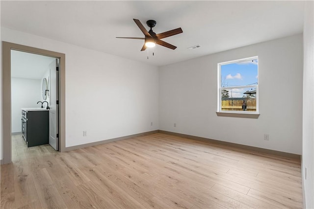 unfurnished room featuring sink, light hardwood / wood-style flooring, and ceiling fan