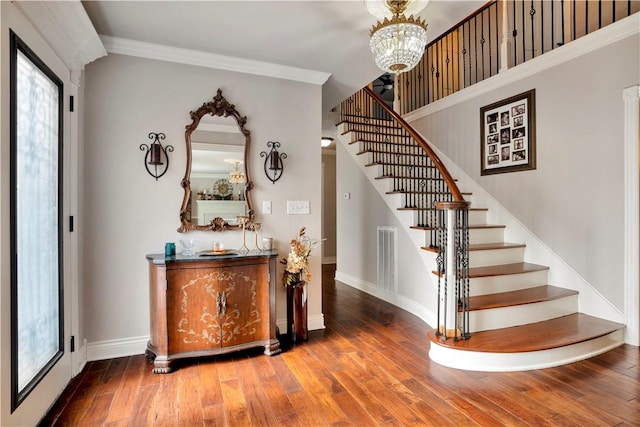 stairway featuring an inviting chandelier, ornamental molding, and wood-type flooring