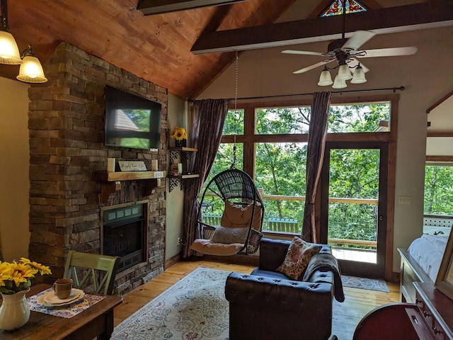 living room featuring lofted ceiling with beams, ceiling fan, a fireplace, and light hardwood / wood-style floors