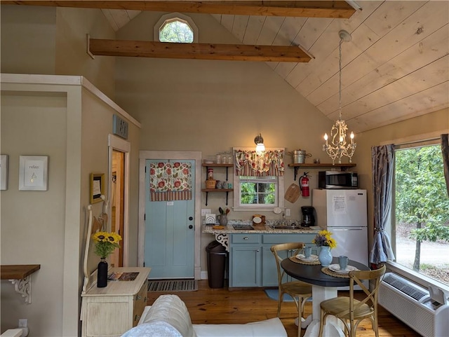 kitchen with white refrigerator, plenty of natural light, vaulted ceiling with beams, and decorative light fixtures