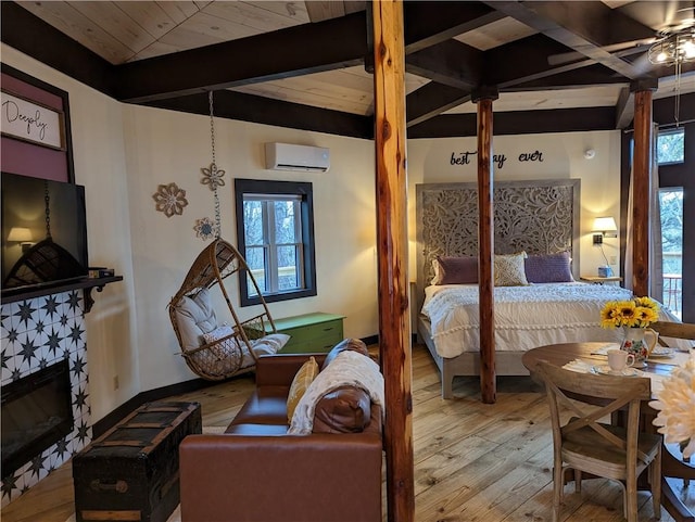 bedroom with a tiled fireplace, hardwood / wood-style floors, multiple windows, and an AC wall unit