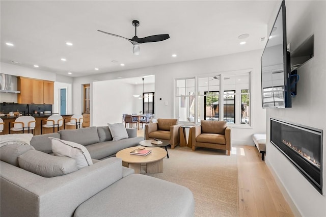 living room featuring ceiling fan, sink, and light hardwood / wood-style floors