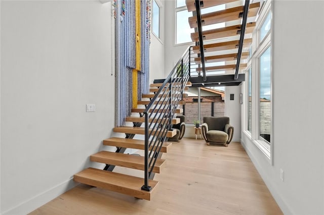 stairway with hardwood / wood-style flooring and a towering ceiling