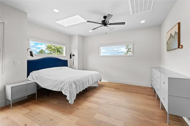 bedroom with a skylight, ceiling fan, and light hardwood / wood-style flooring