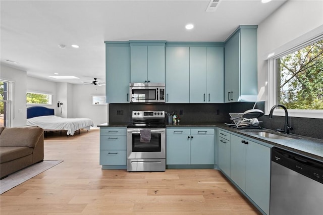 kitchen featuring stainless steel appliances, sink, and blue cabinetry