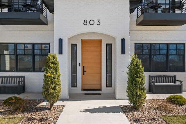 property entrance featuring brick siding and a balcony