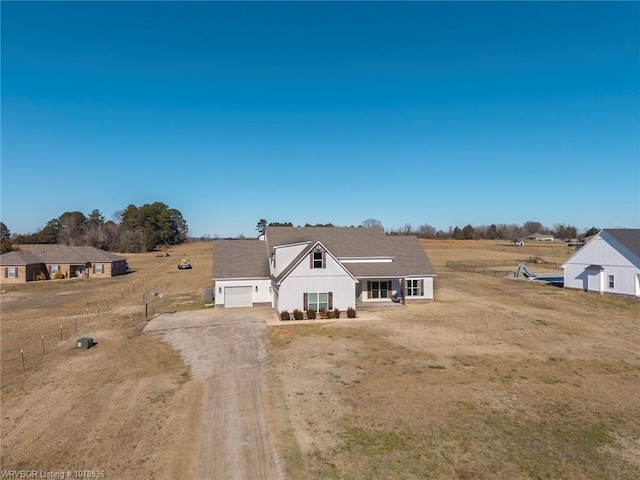 view of front facade featuring covered porch, dirt driveway, a rural view, and a front yard