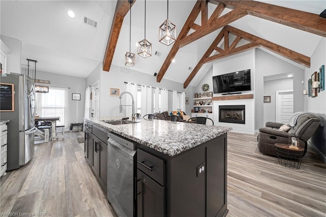 kitchen with decorative light fixtures, a center island with sink, visible vents, appliances with stainless steel finishes, and open floor plan