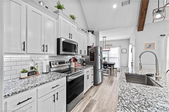 kitchen featuring appliances with stainless steel finishes, a sink, visible vents, and white cabinets