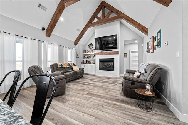 living area featuring high vaulted ceiling, a fireplace, visible vents, light wood-style floors, and beamed ceiling