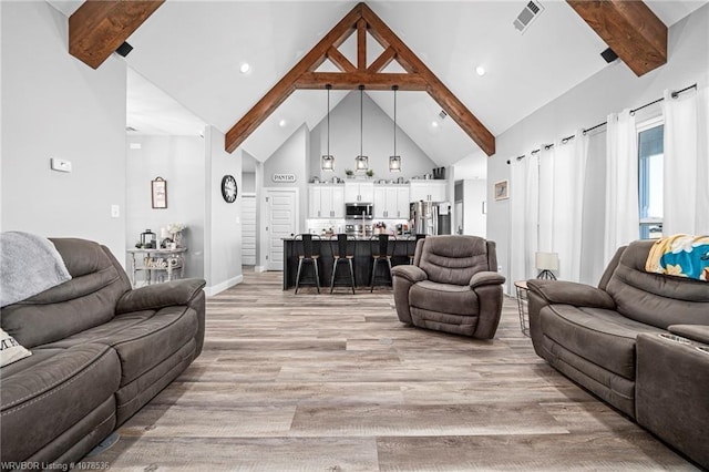 living room with high vaulted ceiling, light wood-style flooring, beamed ceiling, and visible vents