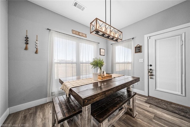 dining area with wood finished floors, visible vents, and baseboards