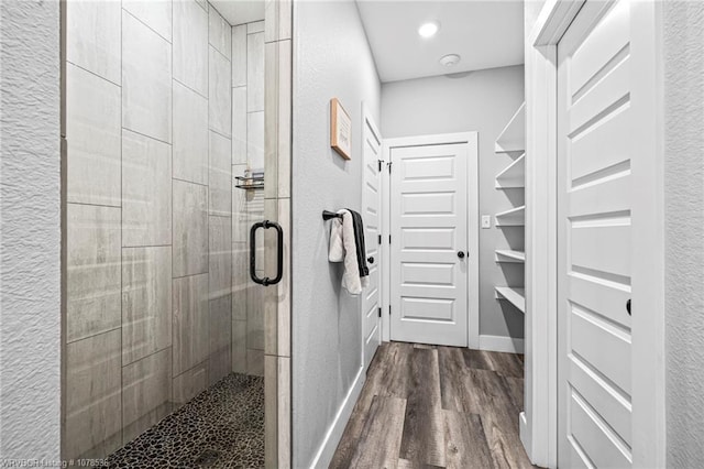 full bathroom with recessed lighting, a textured wall, a stall shower, wood finished floors, and baseboards