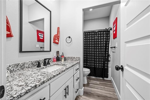 full bathroom with toilet, a shower with shower curtain, wood finished floors, vanity, and baseboards