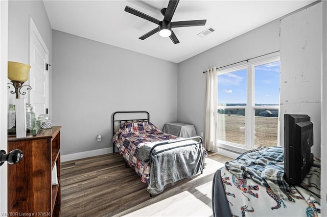 bedroom featuring a ceiling fan, wood finished floors, visible vents, and baseboards