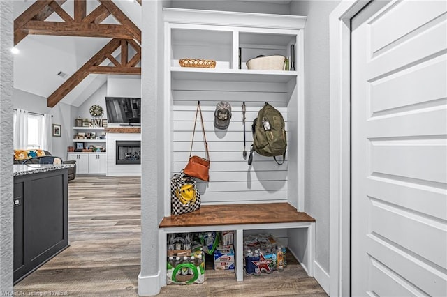 mudroom featuring visible vents, a fireplace, lofted ceiling with beams, and wood finished floors