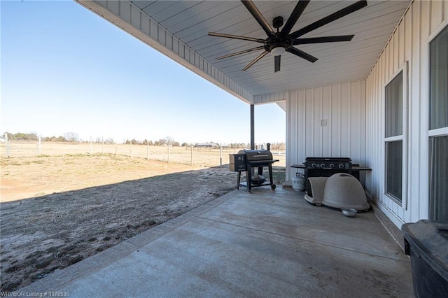 view of patio with a grill, fence, a ceiling fan, and a rural view