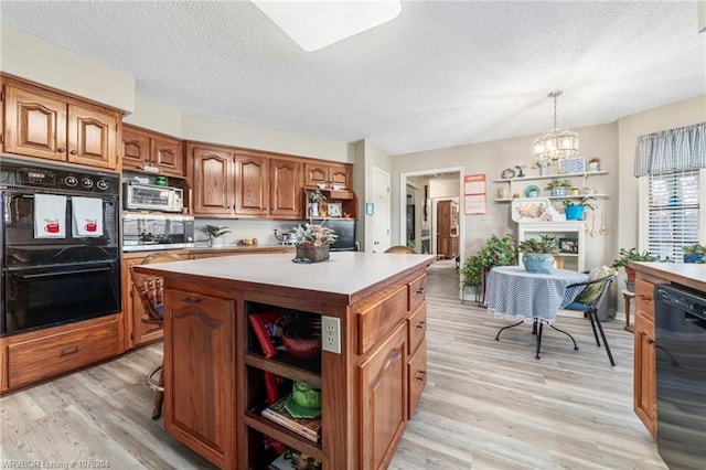 kitchen featuring light countertops, hanging light fixtures, a center island, black appliances, and brown cabinetry