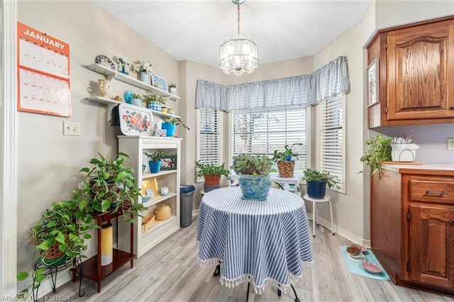 dining area with a notable chandelier, baseboards, and light wood-style floors