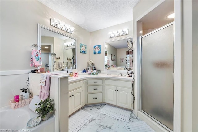 bathroom with marble finish floor, a shower stall, a textured ceiling, and double vanity