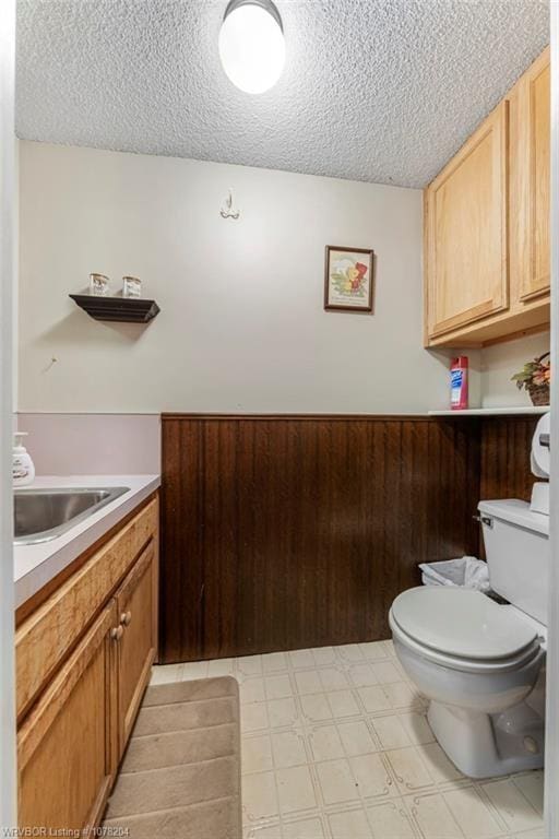 half bath with a textured ceiling, vanity, toilet, and tile patterned floors