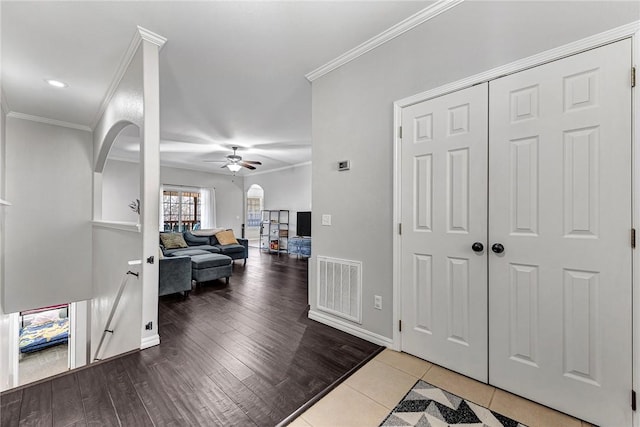 foyer featuring crown molding, ceiling fan, and light wood-type flooring