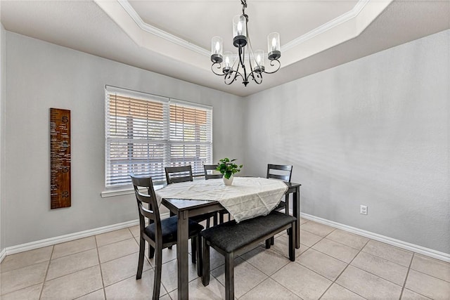 tiled dining space featuring a raised ceiling, crown molding, and an inviting chandelier