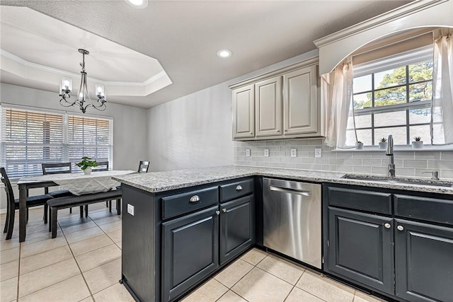 kitchen with light stone counters, a tray ceiling, dishwasher, and sink