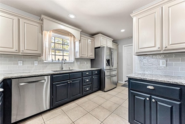 kitchen with light tile patterned flooring, stainless steel appliances, sink, and light stone counters