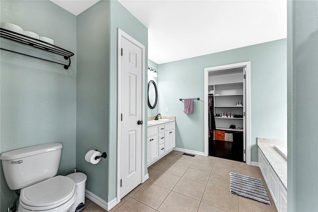 bathroom featuring vanity, a bathing tub, tile patterned floors, and toilet