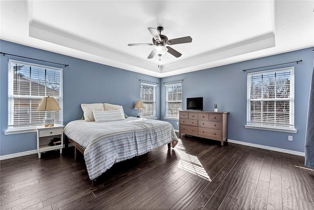 bedroom featuring dark hardwood / wood-style floors, ceiling fan, ornamental molding, and a tray ceiling