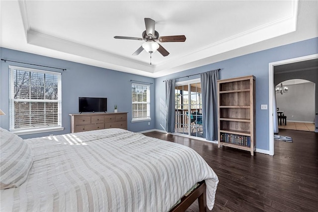 bedroom featuring dark hardwood / wood-style floors, ceiling fan with notable chandelier, a raised ceiling, and access to outside