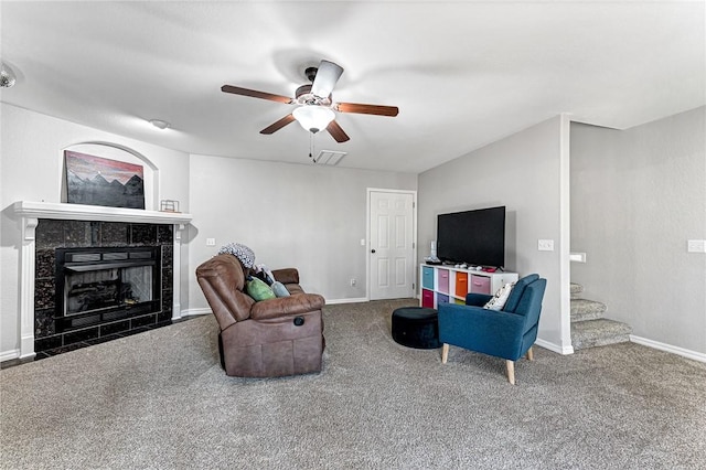 carpeted living room with ceiling fan and a tile fireplace