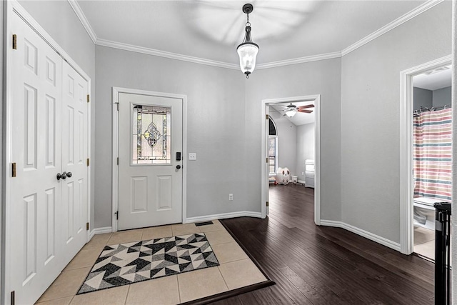 tiled entrance foyer featuring ornamental molding, a healthy amount of sunlight, and ceiling fan