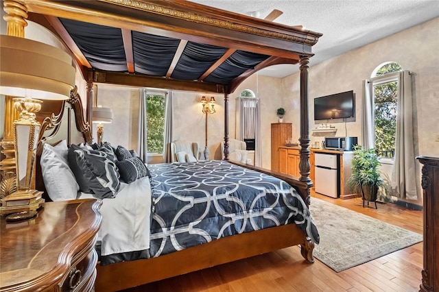 bedroom featuring hardwood / wood-style flooring, fridge, and decorative columns