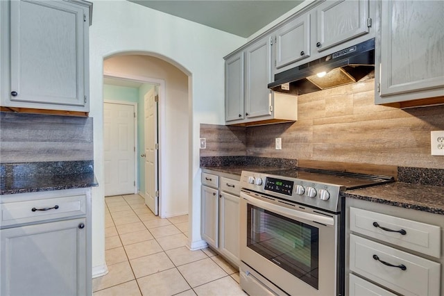 kitchen featuring light tile patterned floors, stainless steel electric range, gray cabinetry, decorative backsplash, and dark stone counters